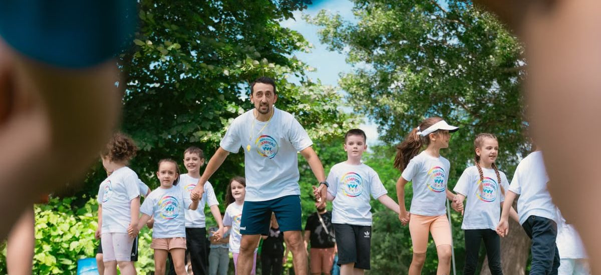 Children and an instructor playing together in a sunny park, holding hands and enjoying outdoor activities.